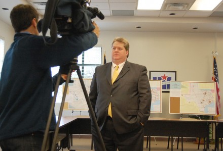 After the release of the 2012-14 Reclassification and Realignment, Dr. Mark Cousins, the athletic director, gives an interview to a local cable news station. The maps that the staff creates for each district within a conference stand in the background.