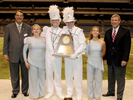 George Strickland from UIL and Mike Brashear, the Executive Director of the Texas Bandmasters Association stand with the 3A State Marching Band Champions — Argyle High School.